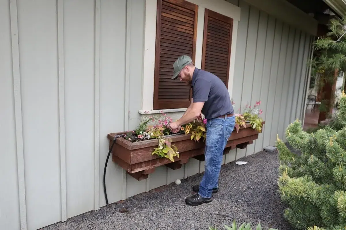 Greenscape Landscaping professional refreshing flower boxes during spring yard cleanup, enhancing curb appeal.