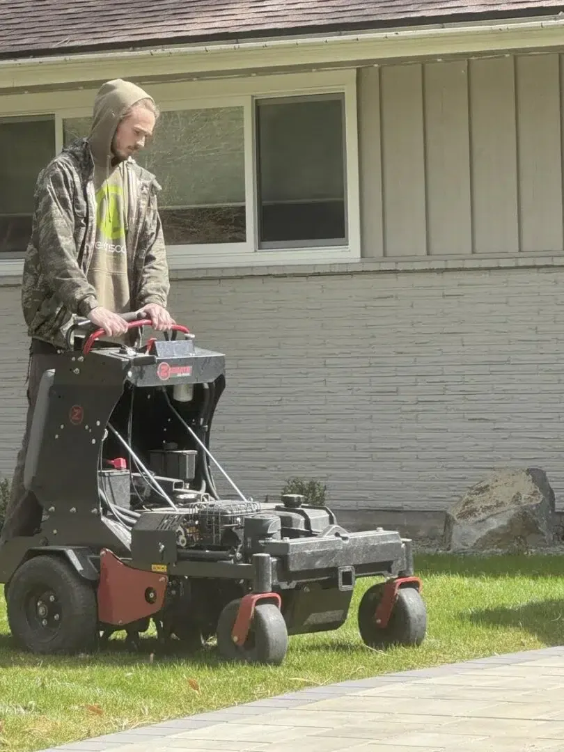 Greenscape Landscaping technician using professional dethatching equipment to power rake and refresh the lawn surface