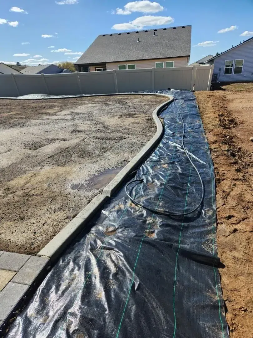 Landscape fabric and trench layout in progress for a new sprinkler system installation in a residential yard.