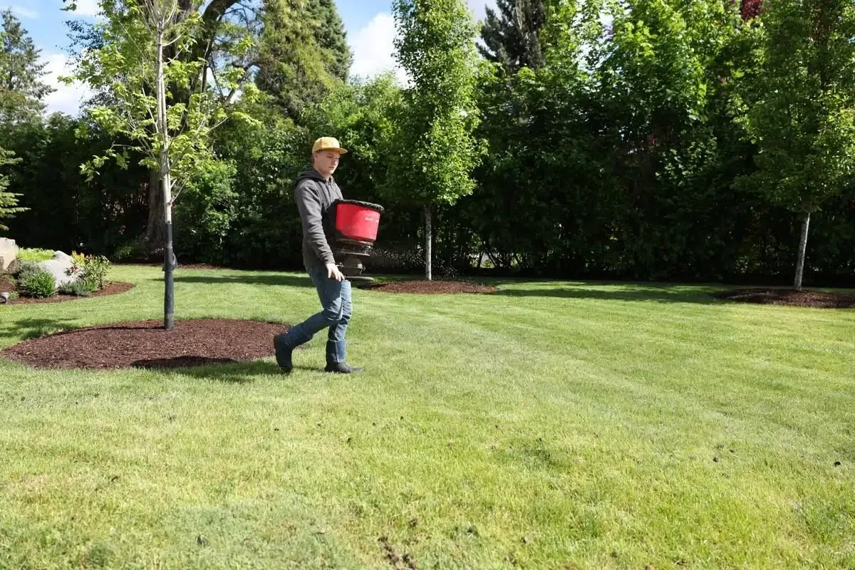 Technician applying lawn treatment to prevent and control turf disease in a spacious green yard.