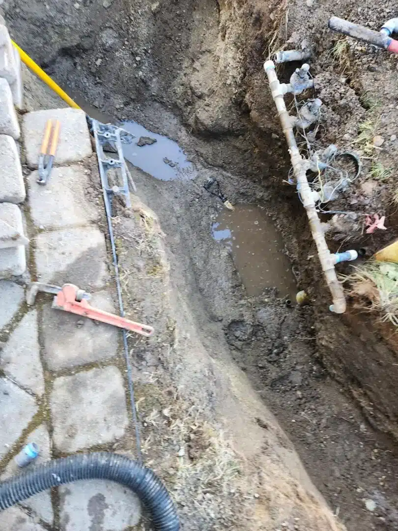 Sprinkler repair in progress by Greenscape Landscaping of Spokane, showing exposed valve system and irrigation lines