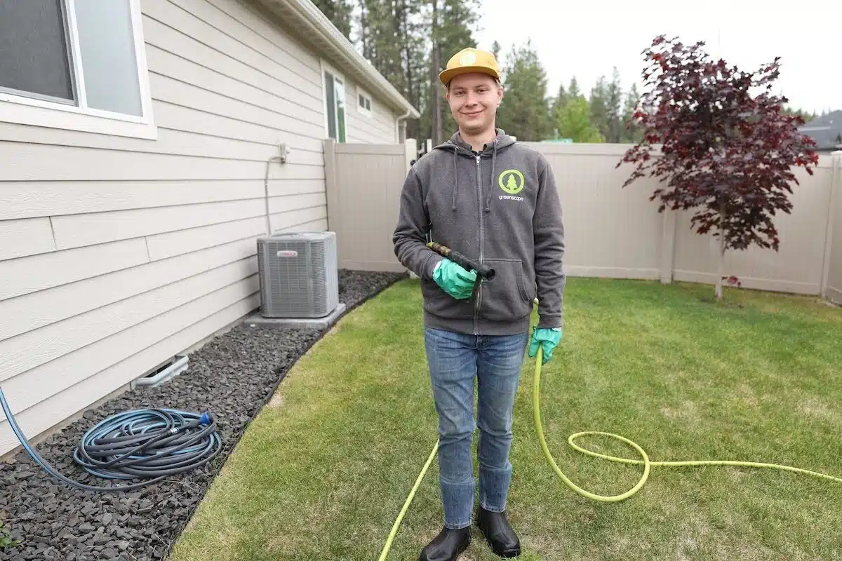 Greenscape Landscaping technician spraying fertilizer at a customers house