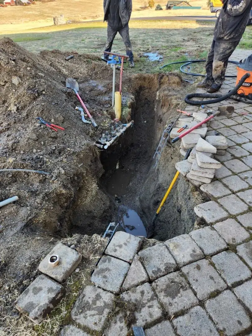 Technicians working on underground piping during a sprinkler system installation, setting the foundation for irrigation lines.