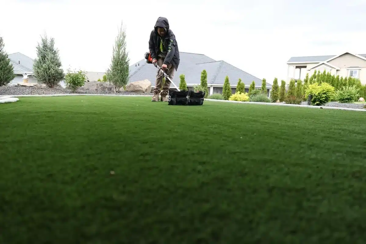 Worker pushing a lawn aerator to perform lawn aeration on a residential lawn