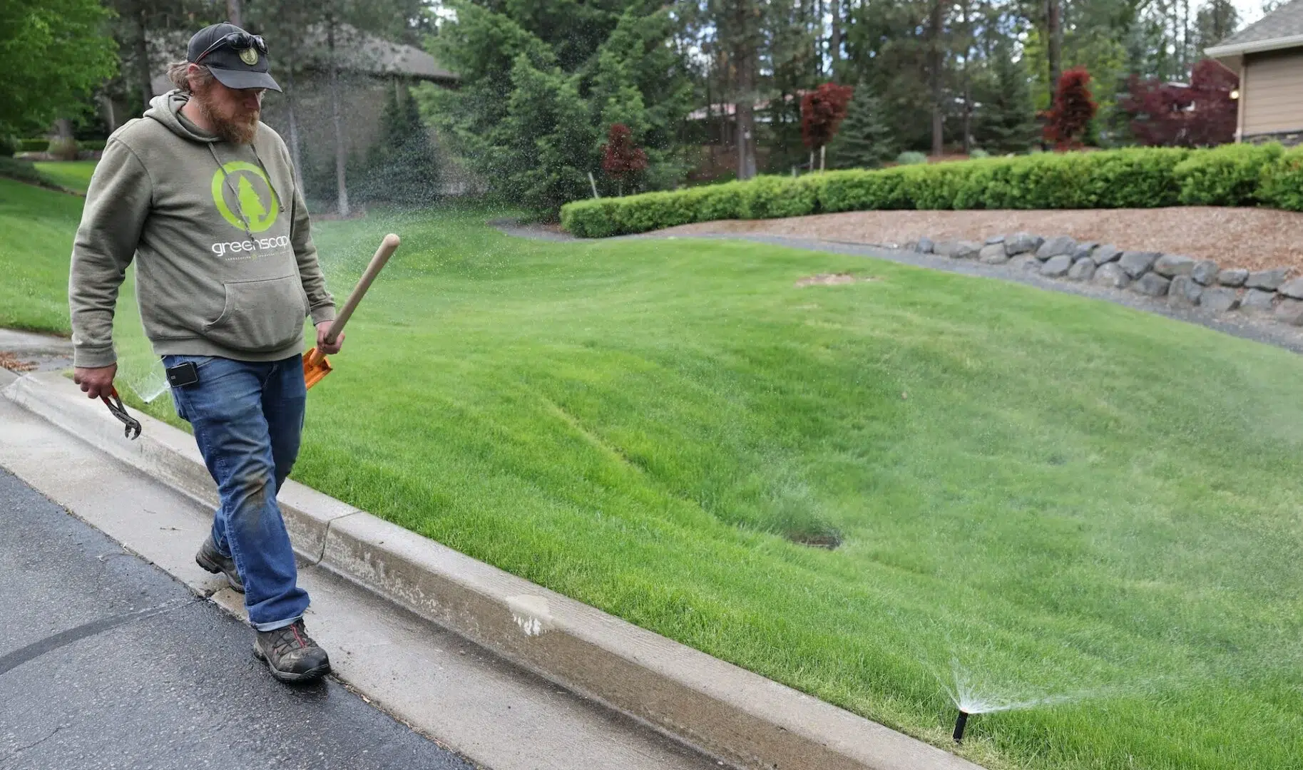 Greenscape Landscaping employee fixing broken sprinklers in Spokane Washington