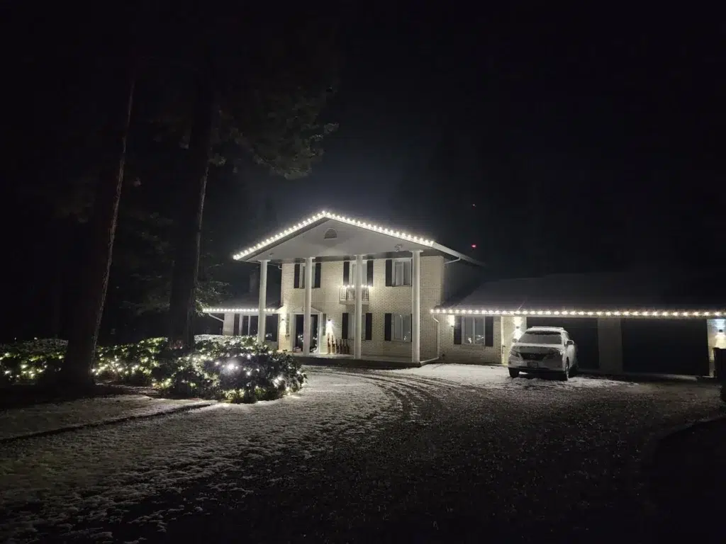 White LED Christmas lights outlining a two-story Spokane home, installed by Greenscape Landscaping.