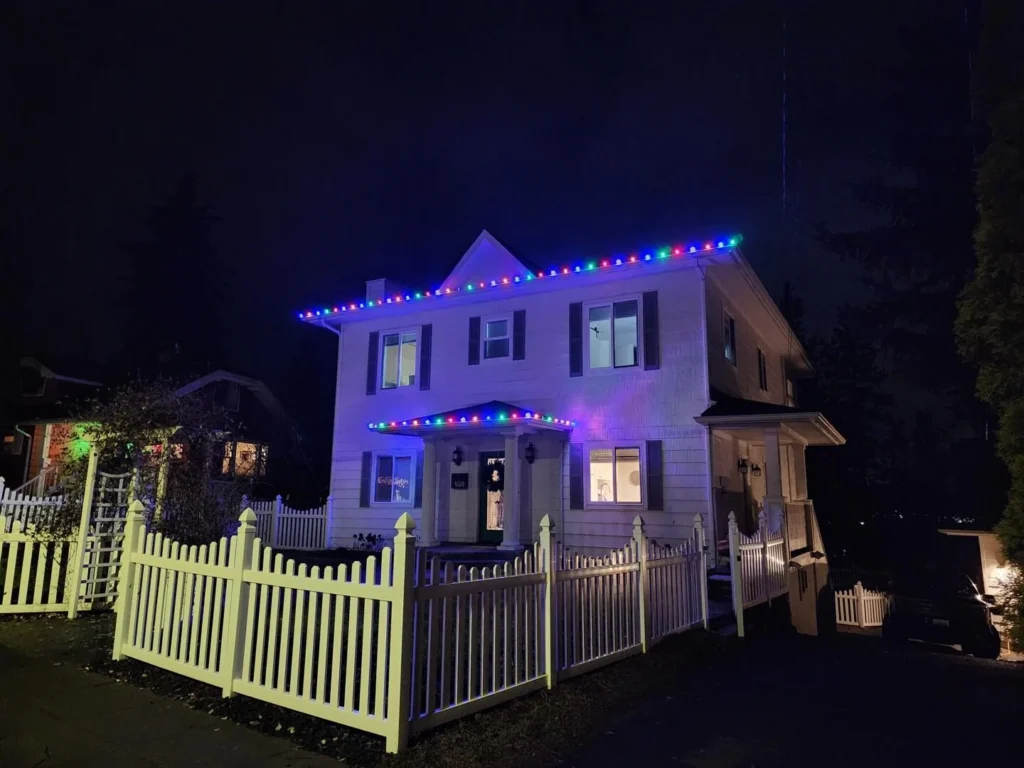 Two-story Spokane home with elegant white Christmas lights installed by Greenscape Landscaping.